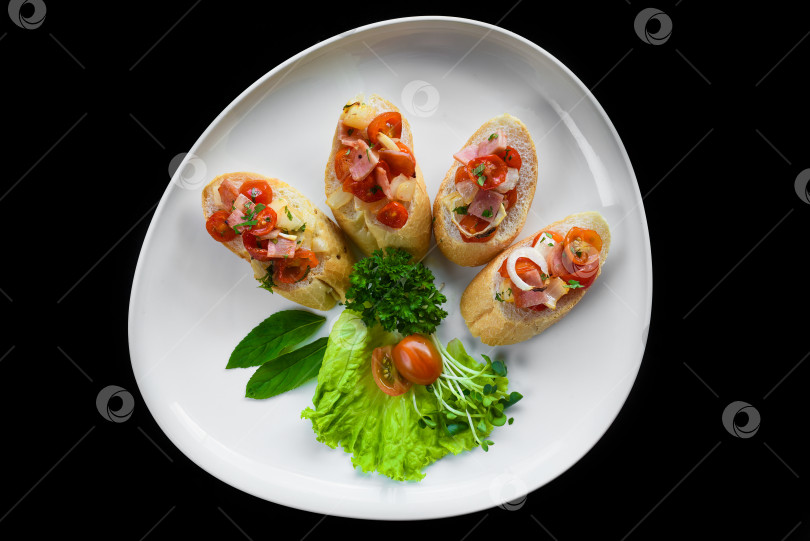 Скачать Брускетта с помидорами, ветчиной, луком и оливковым маслом на белой тарелке крупным планом фотосток Ozero