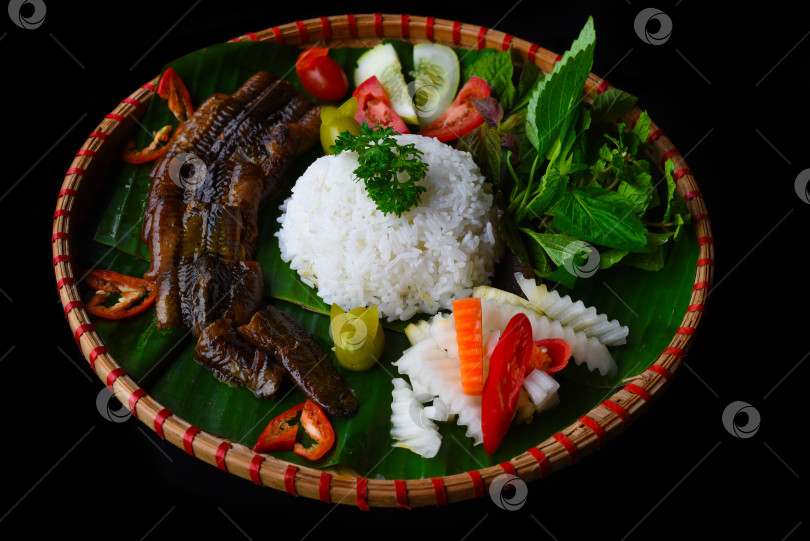 Скачать Копченый угорь с рисом и овощами на черном фоне, вид сбоку фотосток Ozero