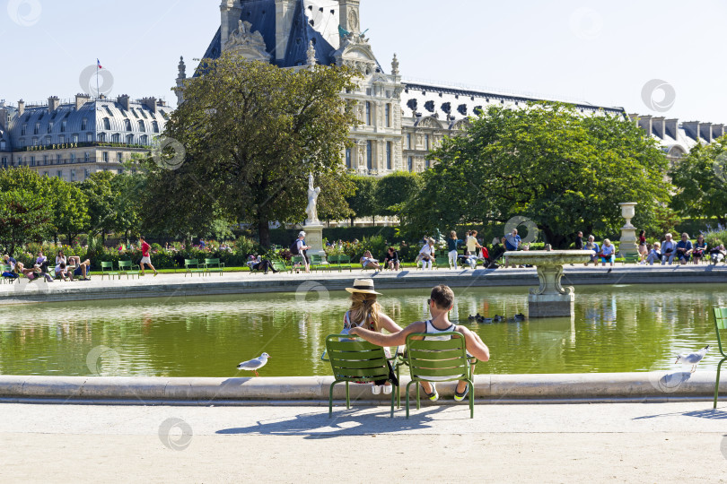 Скачать Мужчина и женщина отдыхают у пруда в саду Тюильри. Париж, Франция. фотосток Ozero