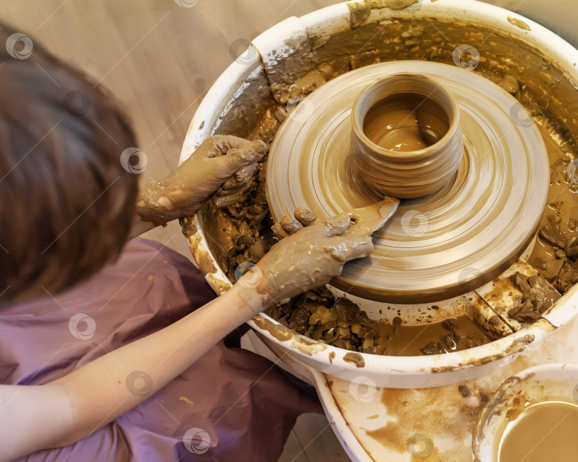 Скачать Мальчик делает керамический горшок на гончарном круге в мастерской фотосток Ozero