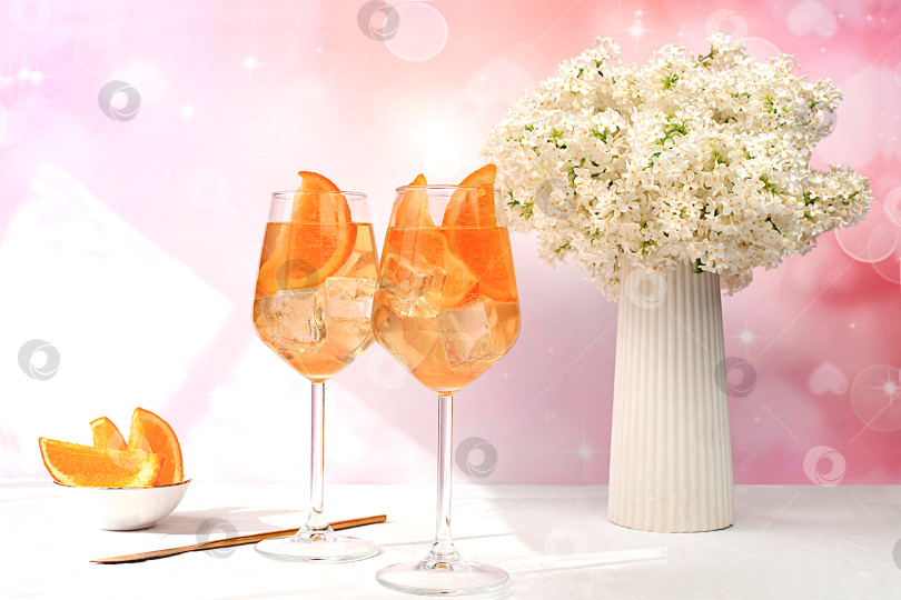 Скачать Праздничный алкогольный коктейль Aperol spritz в бокалах на ярком фоне с букетом сирени, концепция летнего бара, алкогольные напитки на вечеринке, реклама ресторанов и кафе, фотосток Ozero