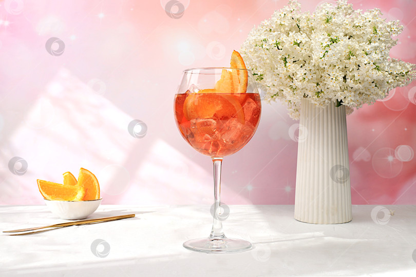 Скачать Праздничный алкогольный коктейль Aperol spritz в бокалах на ярком фоне с букетом сирени, концепция летнего бара, алкогольные напитки на вечеринке, реклама ресторанов и кафе, фотосток Ozero