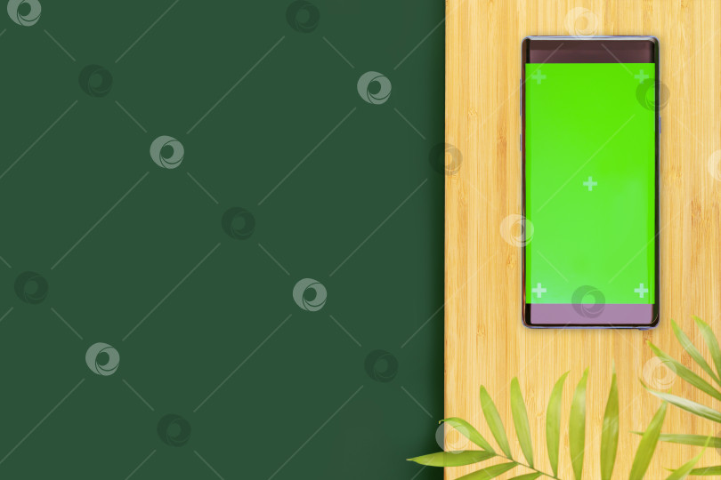 Скачать Зеленый стол и смартфон с зеленым экраном на деревянной доске фотосток Ozero
