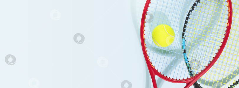 Скачать Желтый теннисный мяч и теннисные ракетки на синем фоне фотосток Ozero
