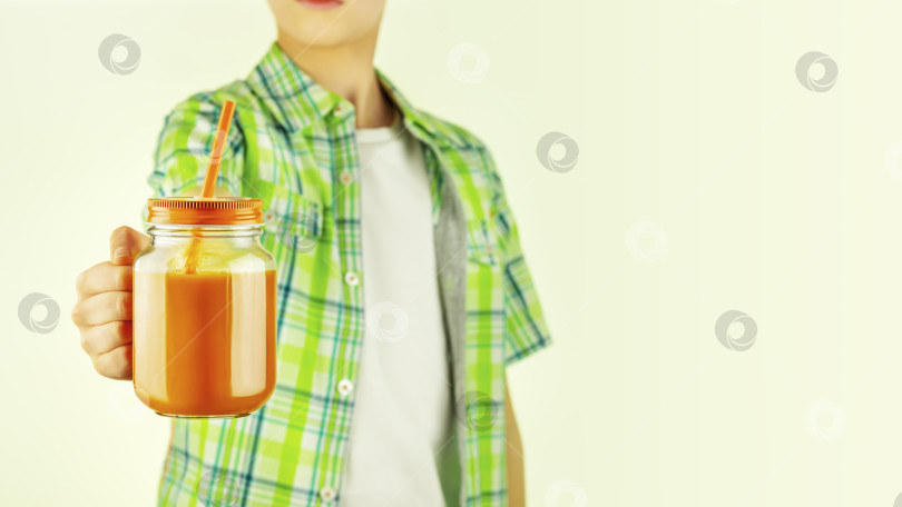 Скачать подросток держит морковный сок в стеклянной кружке с пробелом для копирования фотосток Ozero