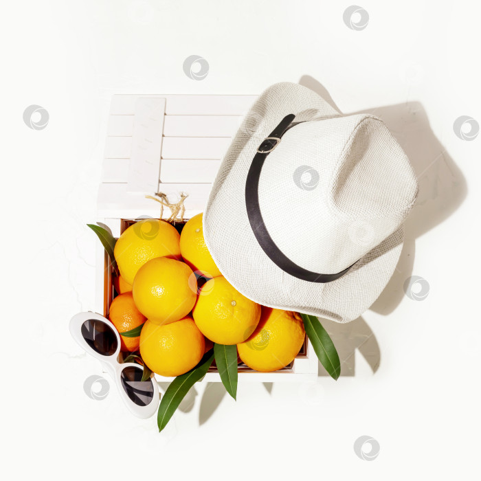 Скачать Апельсины в деревянной коробке с летней шляпой и солнцезащитными очками на белом фоне фотосток Ozero
