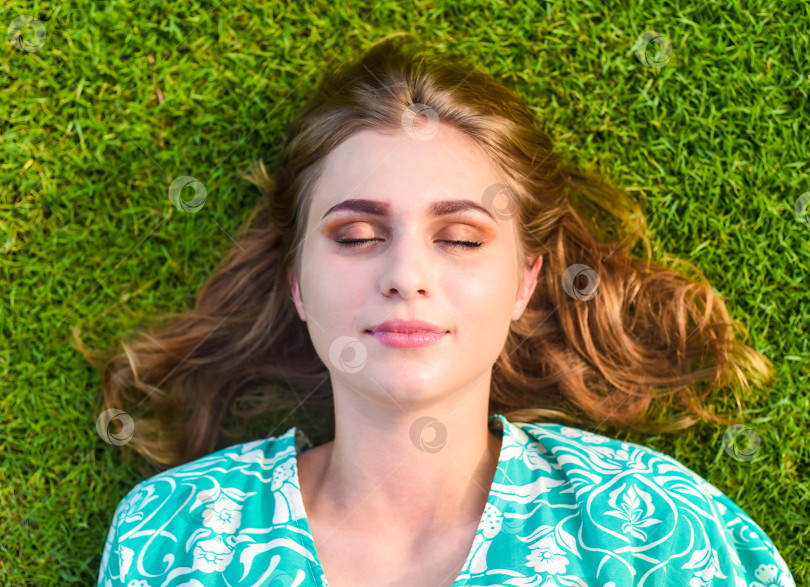Скачать Красивая белорусская женщина спит, лежа на траве с закрытыми глазами фотосток Ozero