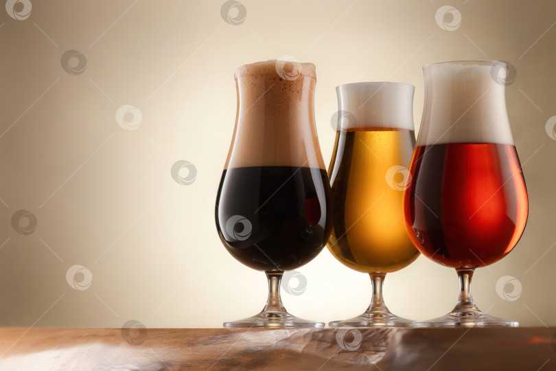 Скачать Три бокала, наполненных разными сортами пива, стоят на деревянной столешнице. фотосток Ozero