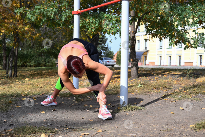 Скачать Спортсмен в удобной спортивной одежде. Фитнес на открытом воздухе в городе. Здоровый образ жизни. Тренер занимается на улице. Уверенная в себе женщина делает тренировку. фотосток Ozero