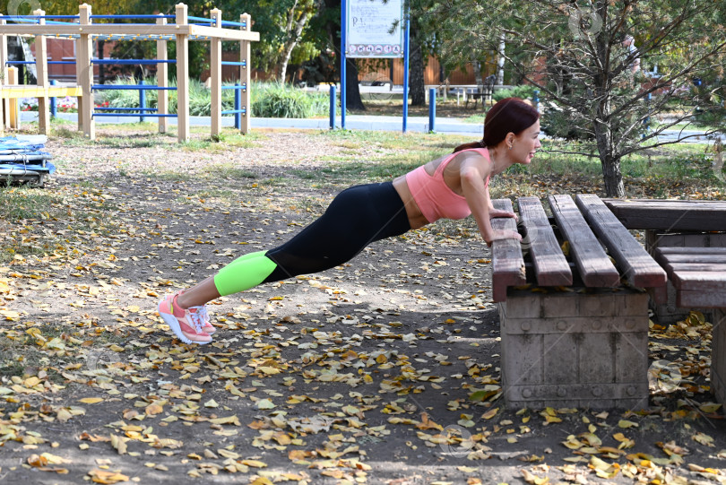 Скачать Спортсмен в удобной спортивной одежде. Фитнес на открытом воздухе в городе. Здоровый образ жизни. Тренер занимается на улице. Уверенная в себе женщина делает тренировку. фотосток Ozero