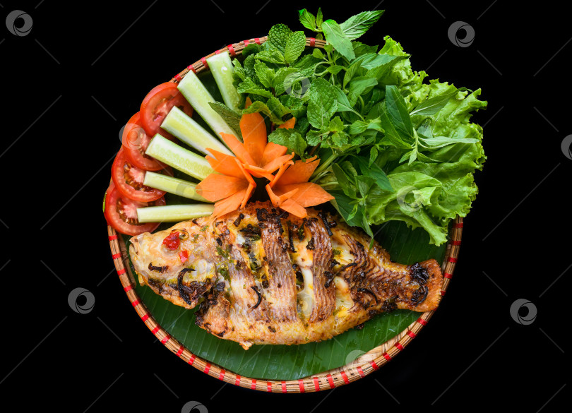 Скачать Вьетнамская жареная рыба с зеленью и овощами на черном фоне фотосток Ozero