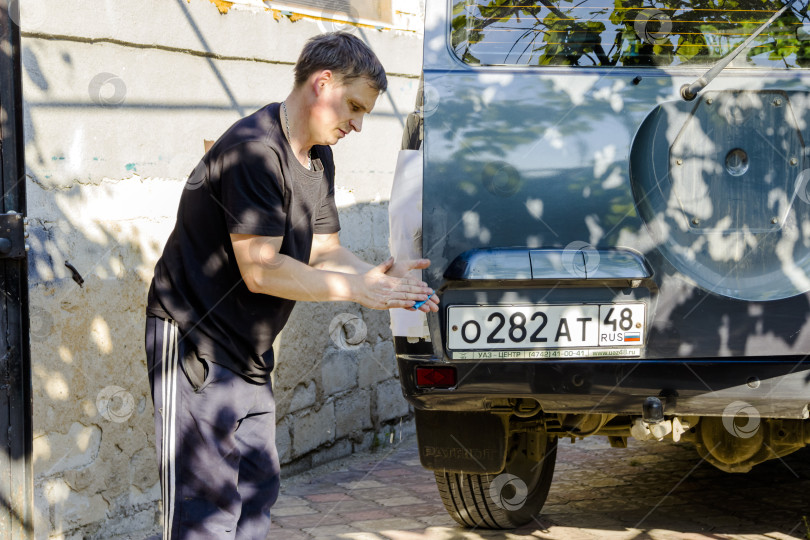 Скачать На снимке мужчина моет свою машину под высоким давлением воды на открытом воздухе. фотосток Ozero