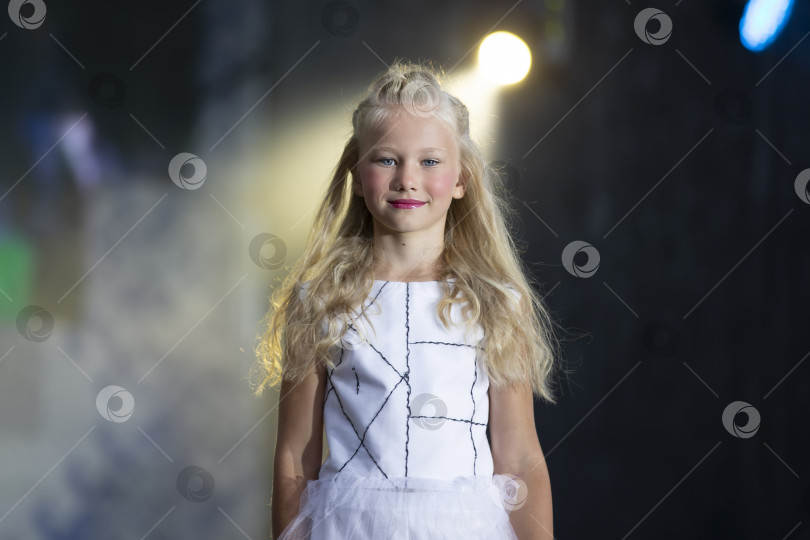 Скачать Маленькая белокурая девочка-модель на светлом фоне сцены. фотосток Ozero