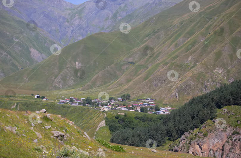 Скачать Красочный пейзаж с высокими горами, красивой извилистой дорогой, зеленым лесом, маленькой деревней. Горная долина. Путешествие по Грузии фотосток Ozero