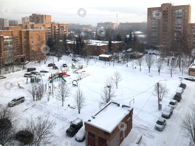 Скачать Вид сверху из окна на заснеженный двор с детской площадкой в зимний день фотосток Ozero