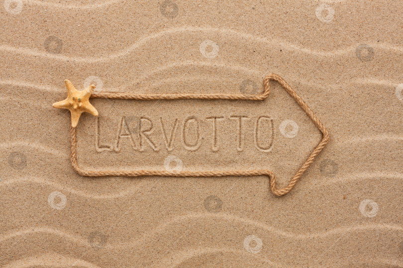Скачать Стрела из веревки и морская звезда с надписью "Ларвотто" на песке фотосток Ozero
