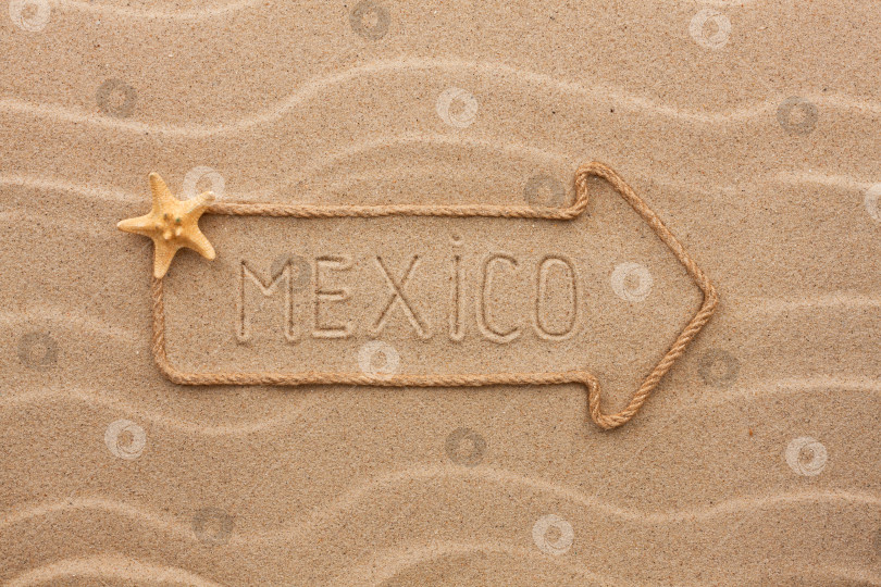 Скачать Стрела из веревки и морских раковин с надписью "Мексика" на песке фотосток Ozero