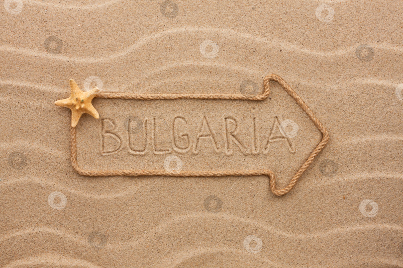 Скачать Стрела из веревки и морских раковин с надписью "Болгария" на песке фотосток Ozero