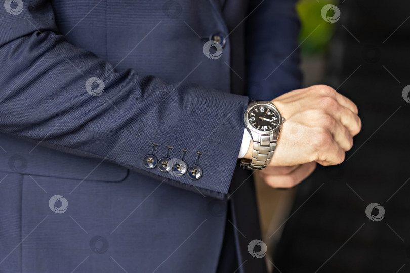 Скачать Крупный план мужских рук. Бизнесмен смотрит на свои часы фотосток Ozero