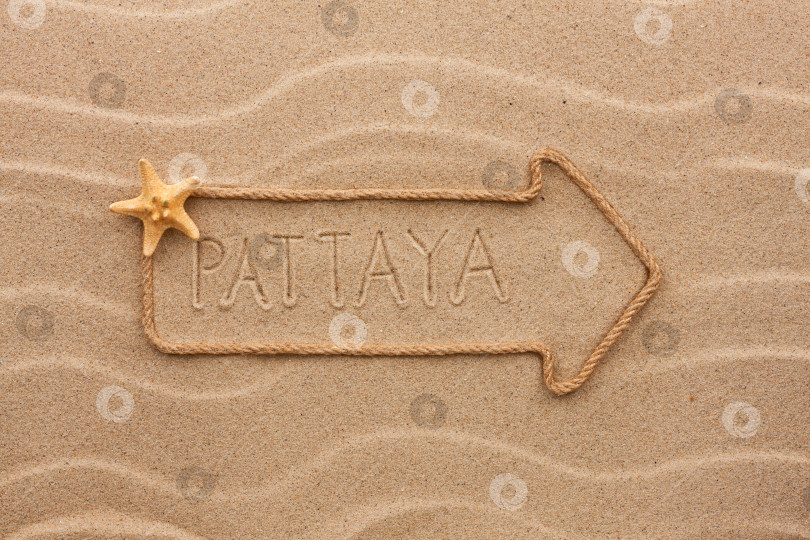 Скачать Стрела из веревки и морских раковин с надписью "Паттайя" на песке фотосток Ozero