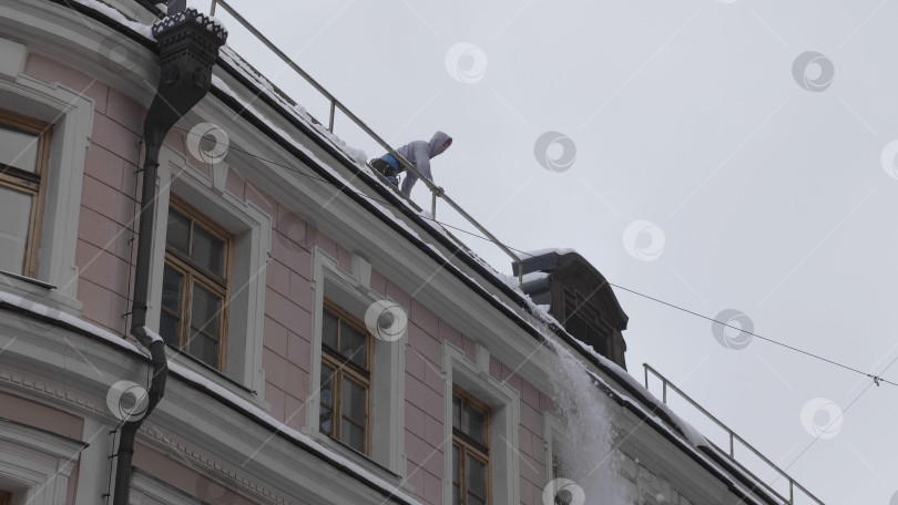 Скачать МОСКВА - 20 декабря 2018 г.: Уборка крыш зданий от снега и наледи зимой с помощью лопаты 20 декабря 2018 г. в Москве, Россия фотосток Ozero