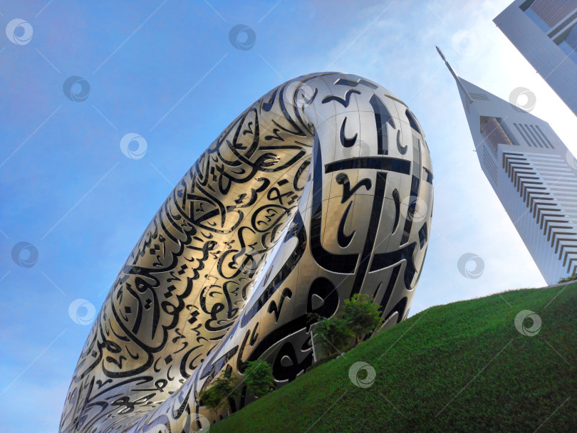 Скачать Дубай, ОАЭ - 26 января 2024 года: Музей будущего, видимый снизу на фоне голубого неба и небоскреба. фотосток Ozero