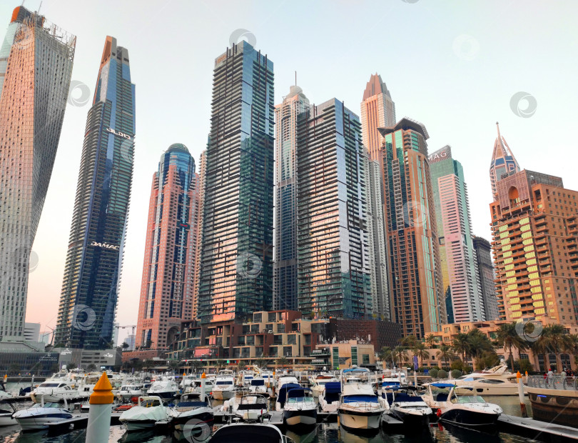 Скачать Дубай, ОАЭ - 22 января 2024 года: Небоскребы в районе Дубай Марина видны с набережной на прекрасном закате. фотосток Ozero