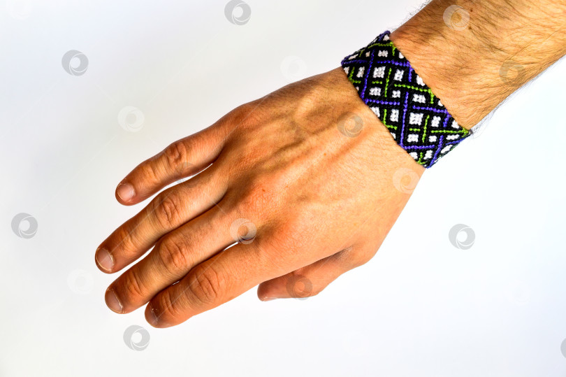 Скачать Мужская рука с красочным браслетом дружбы ручной работы из ниток с узелками, выделенными на белом фоне фотосток Ozero