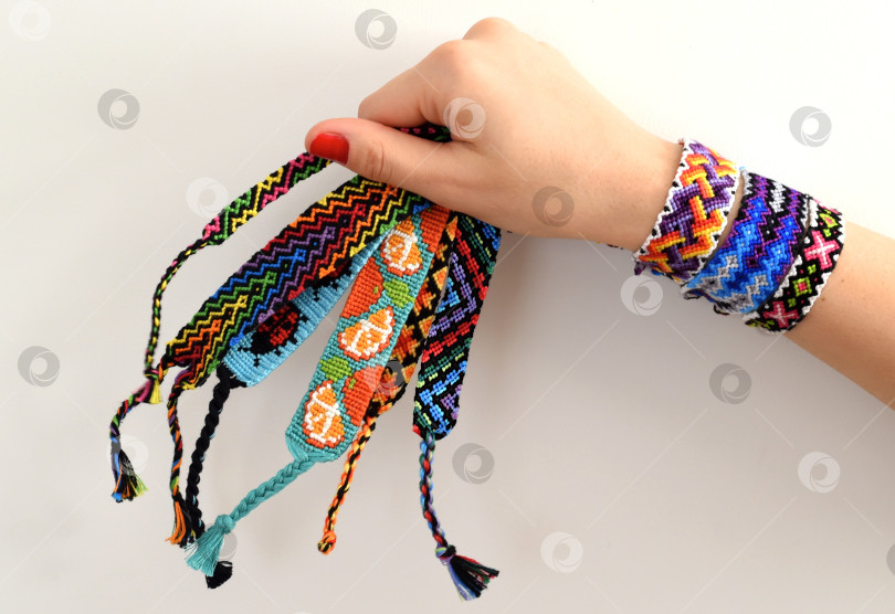 Скачать Женская рука держит плетеные разноцветные браслеты дружбы "Сделай сам" ручной работы из вышивальной нити с узелками фотосток Ozero
