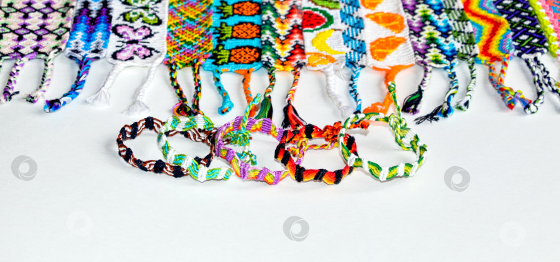 Скачать Разноцветные плетеные браслеты дружбы своими руками ручной работы из вышивки яркой нитью с узелками, выделенными на белом фоне фотосток Ozero
