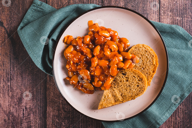 Скачать Крупный план запеченной фасоли с овощами и ржаным хлебом на тарелке на столе вид сверху фотосток Ozero