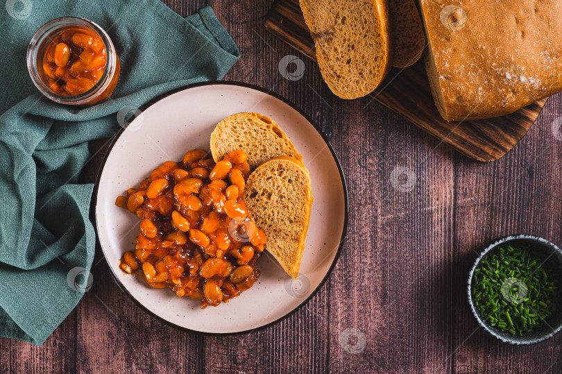 Скачать Запеченная фасоль с овощами и ржаным хлебом на тарелке на столе вид сверху фотосток Ozero