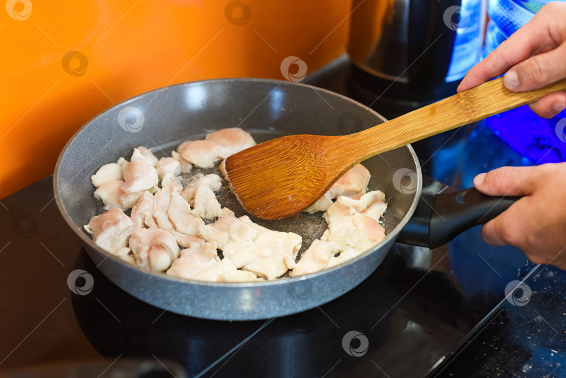 Скачать Руками с помощью лопатки перемешайте обжаренную курицу на сковороде для приготовления японского рамена фотосток Ozero