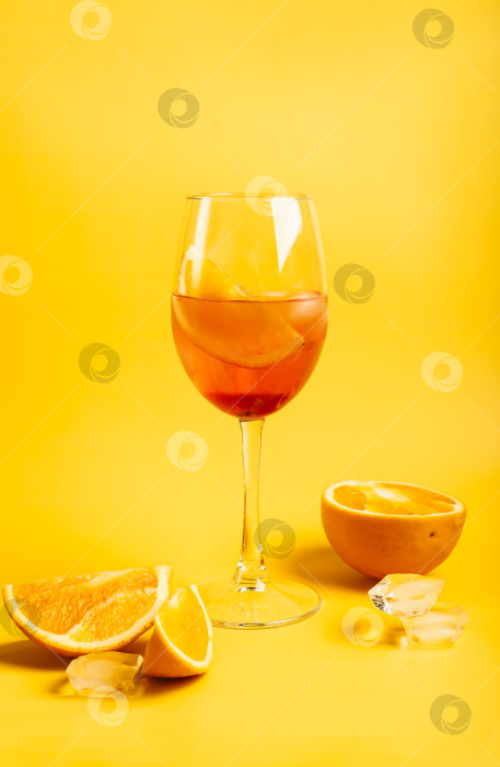 Скачать Коктейль Апероль спритц с апельсинами и льдом на ярко-желтом фоне фотосток Ozero