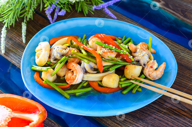 Скачать Азиатское блюдо с морепродуктами и овощами в соевом соусе на тарелке. Смотрите меню азиатской кухни. Крупный план фотосток Ozero