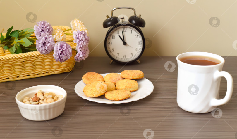 Скачать Круглое домашнее творожное печенье на тарелке рядом с чашкой чая и корзинкой с цветами фотосток Ozero