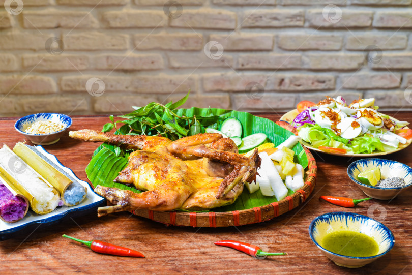 Скачать Курица-гриль по-вьетнамски с разноцветным рисом в бамбуковом соусе и вареными яйцами на деревянном столе фотосток Ozero