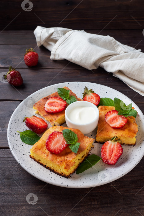 Скачать Творожная запеканка с клубникой и мятой. Вкусный домашний десерт из творога и свежих ягод со сливками. фон из темного дерева, копия пространства. фотосток Ozero