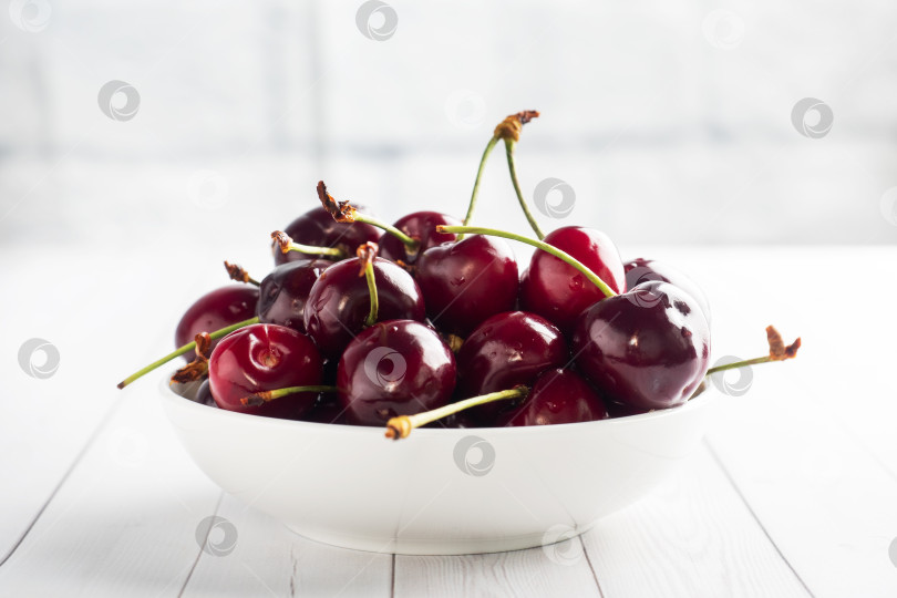 Скачать Спелые сочные ягоды вишни на тарелке. Белый фон. Скопируйте пространство. фотосток Ozero