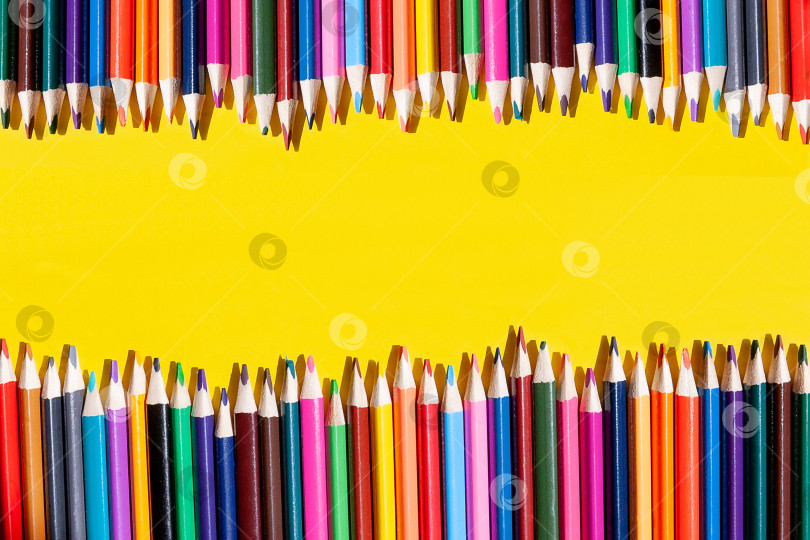 Скачать цветные карандаши лежат рядом друг с другом в виде забора на желтом фоне. Плашмя лежал. Вид сверху. фотосток Ozero