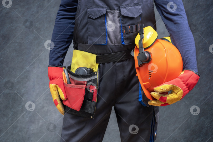 Скачать Строительный рабочий в униформе держит в руках защитную каску. фотосток Ozero