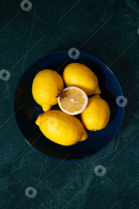 Скачать Лимоны целиком в синем блюде на зеленом фоне фотосток Ozero