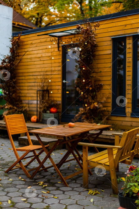 Скачать уютное уличное кафе осенью, садовая деревянная мебель: стол и стулья фотосток Ozero