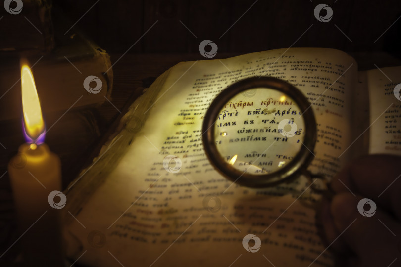 Скачать Прочтите древний текст развернутого тома через увеличительное стекло при свечах фотосток Ozero