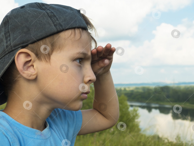 Скачать Маленький мальчик с растрепанной челкой в бейсбольной кепке смотрит на горизонт фотосток Ozero