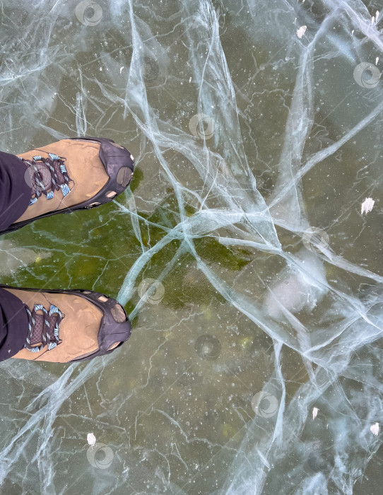 Скачать Нога туриста, стоящего на растрескавшейся поверхности замерзшего озера Байкал в зимний сезон в Сибири, Россия фотосток Ozero