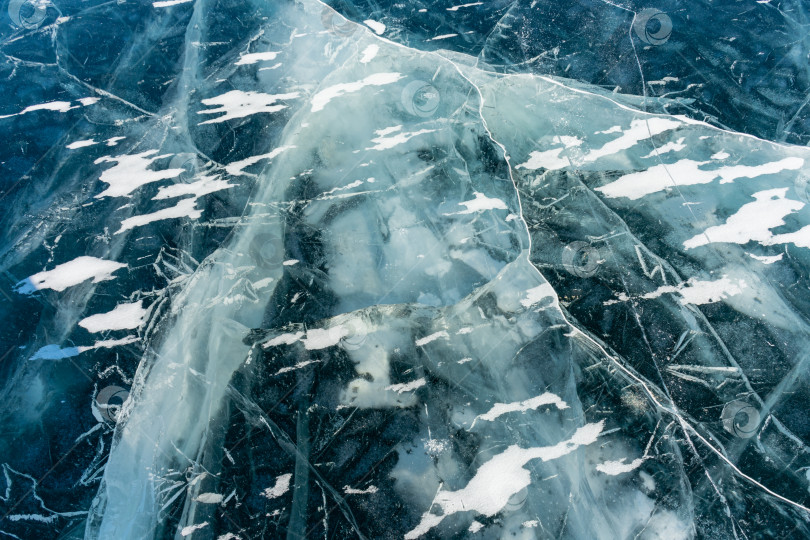 Скачать Естественная текстура зимнего льда с белыми пузырьками и трещинами на замерзшем озере. Абстрактный фон из льда и трещин на поверхности замерзшего озера Байкал. фотосток Ozero