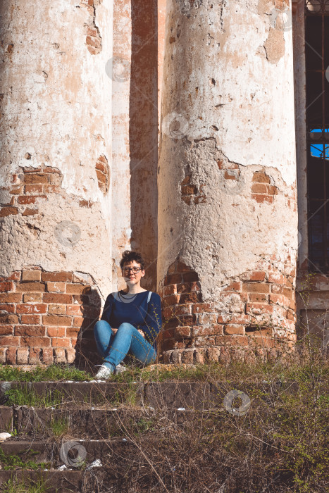 Скачать девушка в очках сидит на фоне заброшенного здания, заброшенной церкви фотосток Ozero
