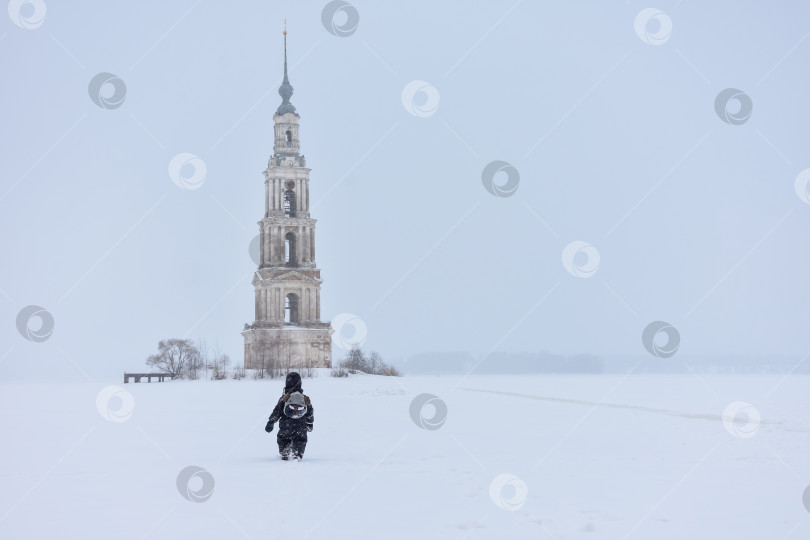 Скачать Колокольня посреди замерзшего озера, ребенок, идущий сзади. фотосток Ozero