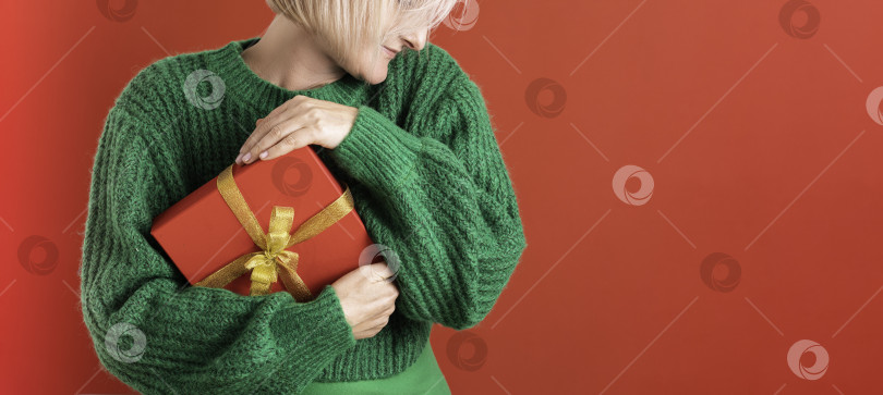 Скачать Красивая улыбающаяся счастливая дама обнимает подарок своей мечты на красном фоне. фотосток Ozero